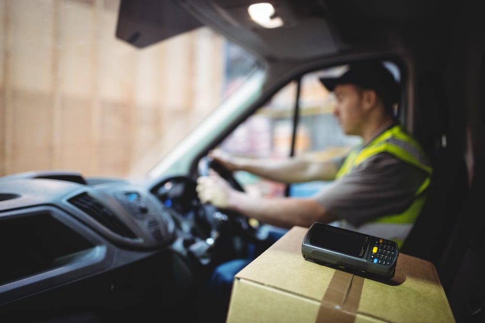 Delivery driver driving van with parcels on seat outside warehouse Delivery driver driving van with parcels on seat outside warehouse
